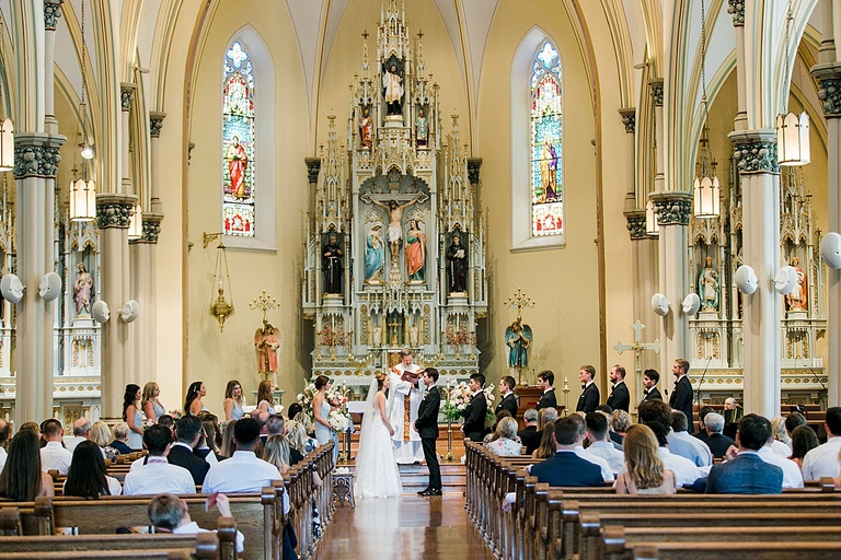 A bride and groom standing at the alter with their wedding party in a Catholic Church in Petoskey