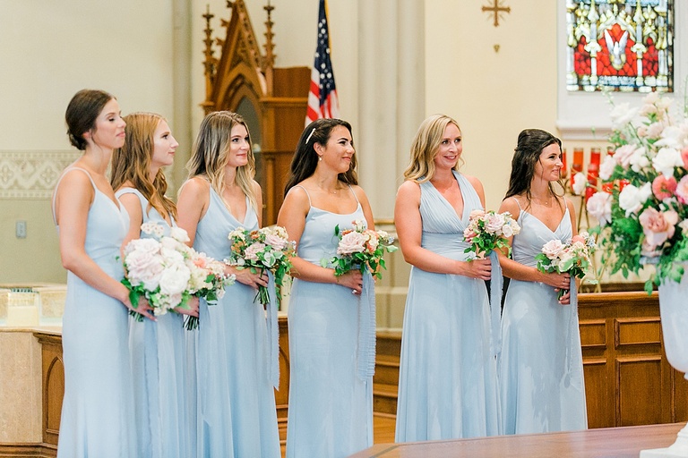 Bridesmaids smiling as they watch the bride and groom exchange vows