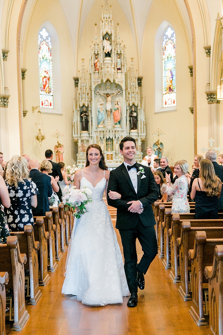 A bride and groom walking down the aisle together and smiling after their wedding ceremony