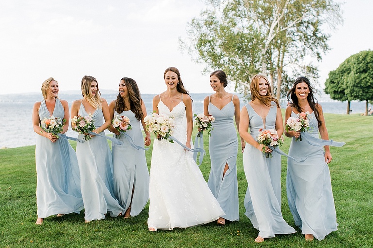 A bride smiling and walking with her bridesmaids in Bayfront park in Petoskey, Michigan