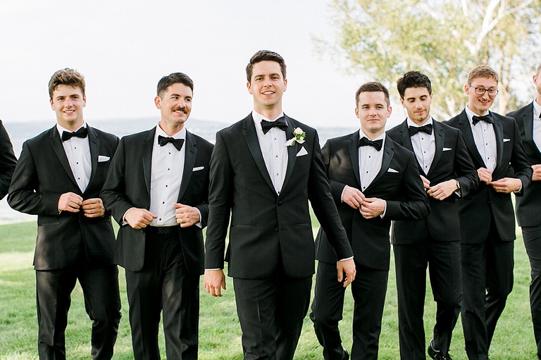 A groom smiling and walking with his groomsmen by his side