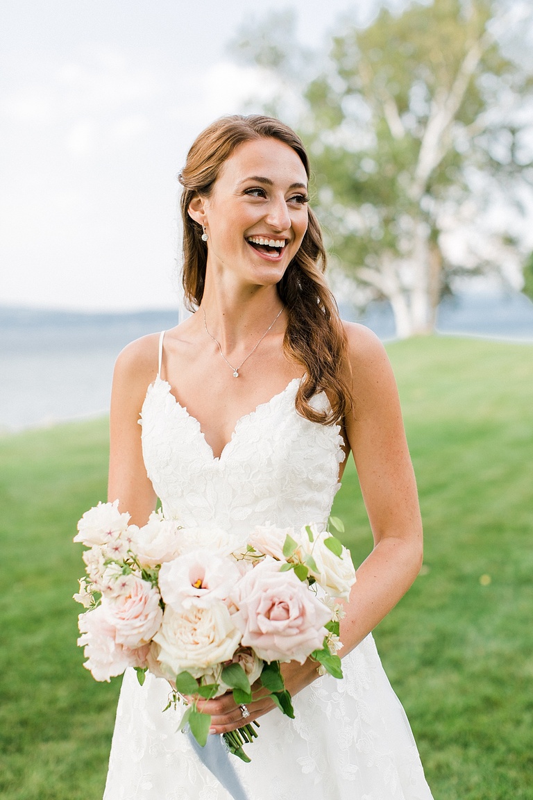 A bride laughing on her wedding day near a lake