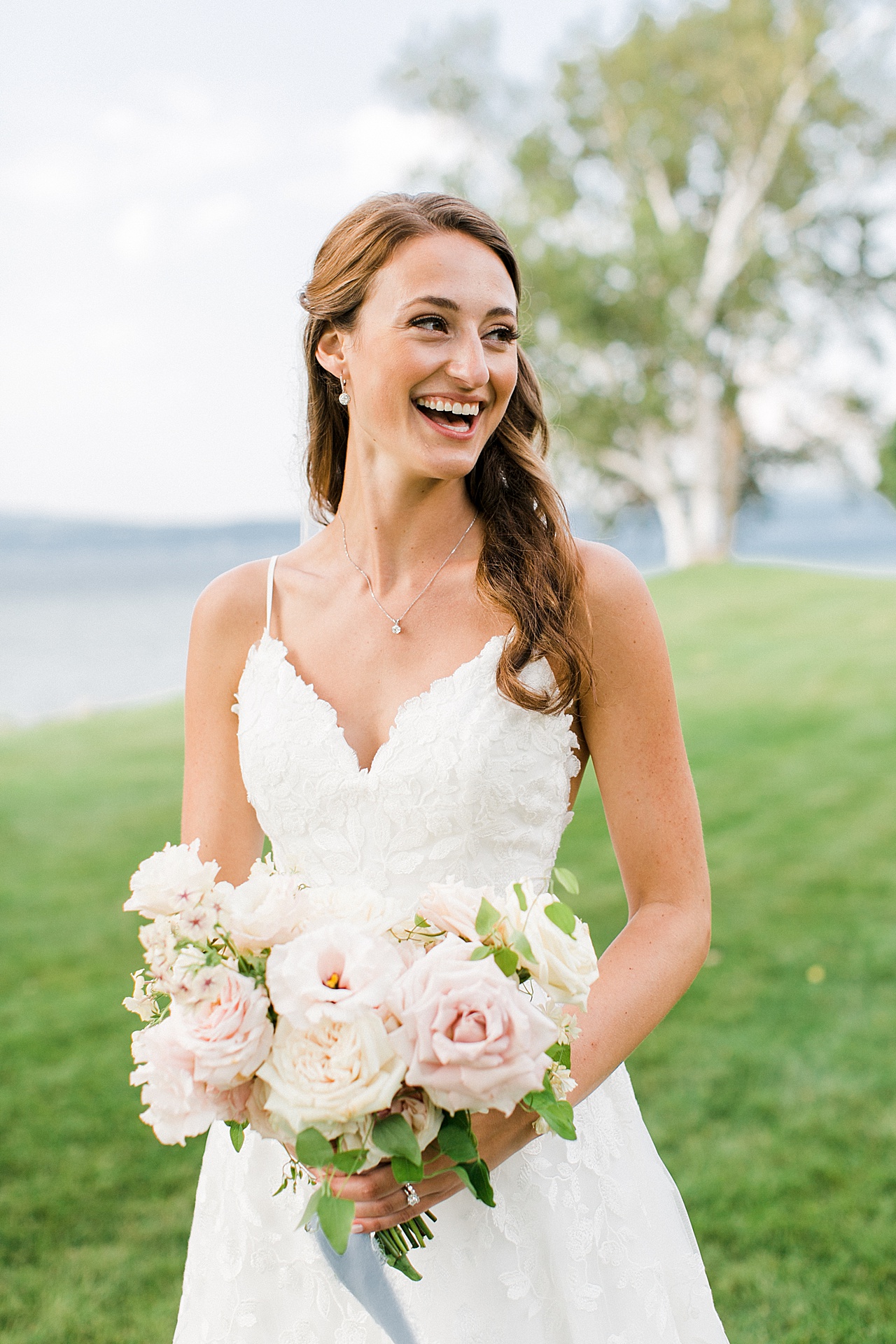 A bride laughing on her wedding day near a lake