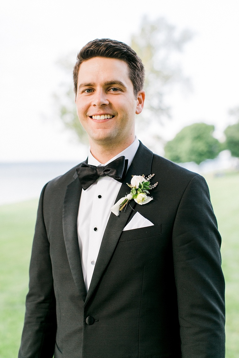 A portrait of a groom in his black tux in a park on a sunny day