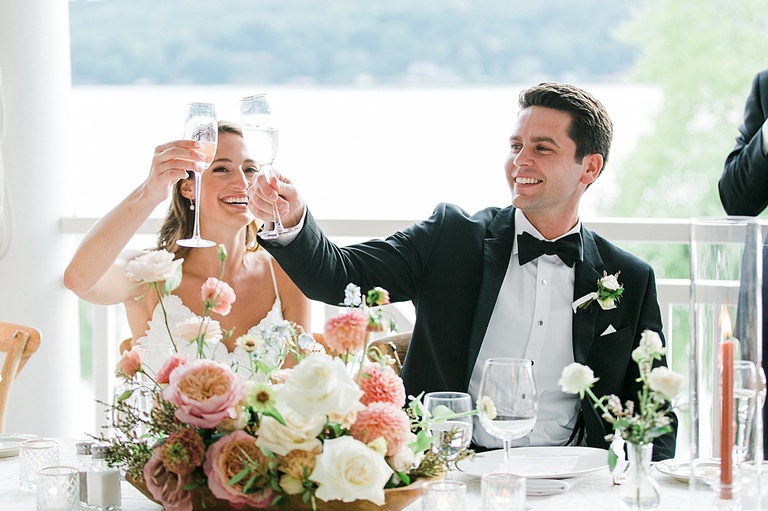 The bride and groom clinking glasses and celebrating with their friends and family at their wedding reception on Walloon Lake