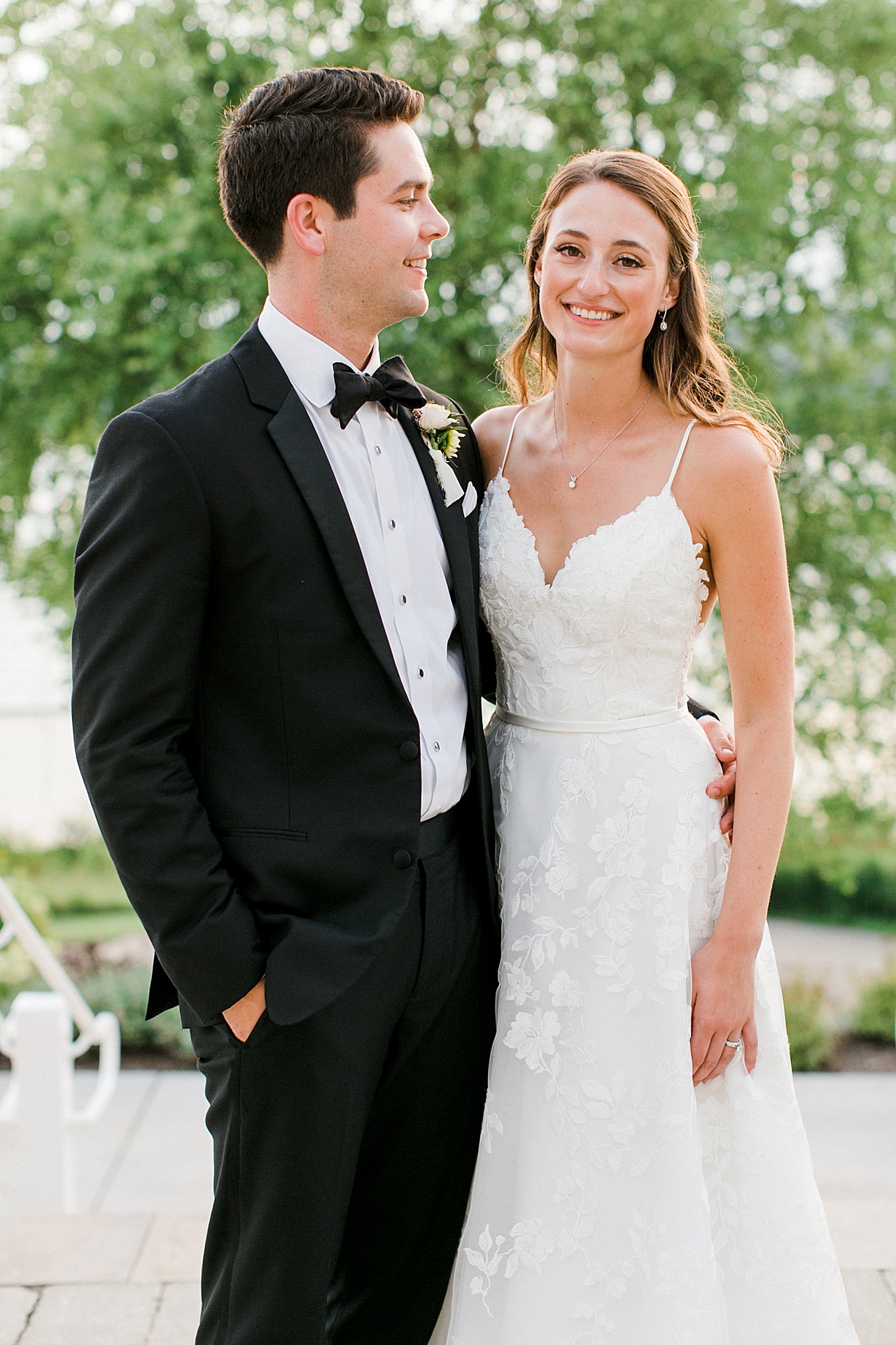 The bride smiling at the camera while the groom gazes lovingly at her