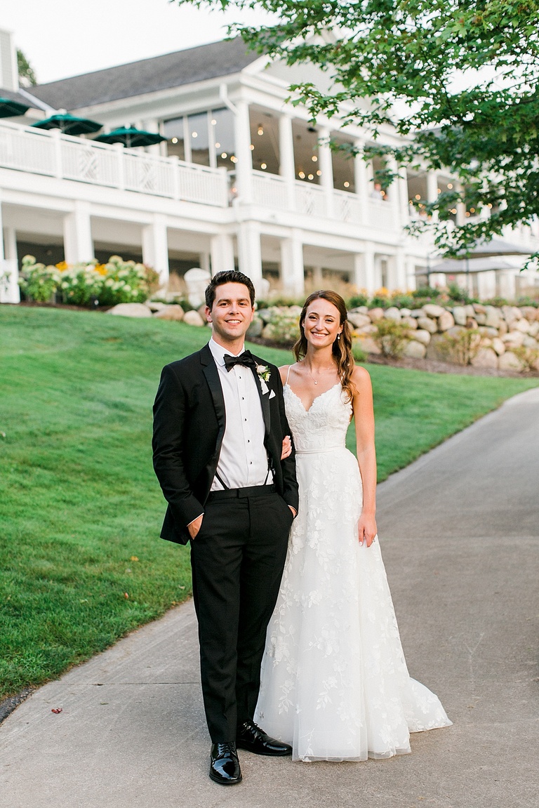 A bride and groom taking portraits in the evening with the Walloon Lake Country Club in the background