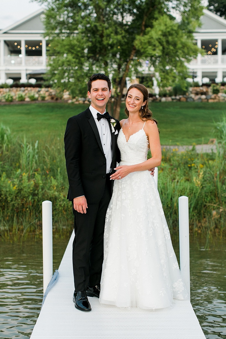 A bride and groom laughing with each other on the docks during sunset portraits on Walloon Lake