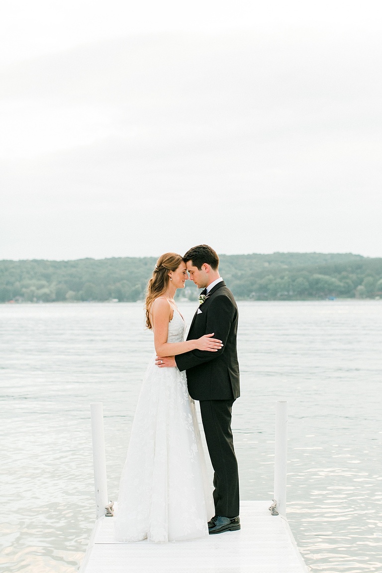 A bride and groom touching foreheads together and soaking in their wedding day on the lake