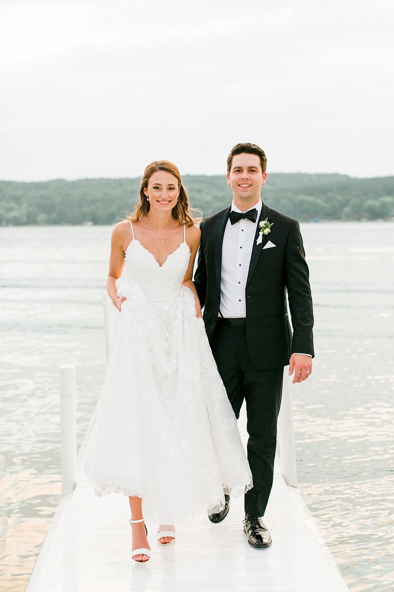 A bride and groom walking together on a dock in Northern Michigan