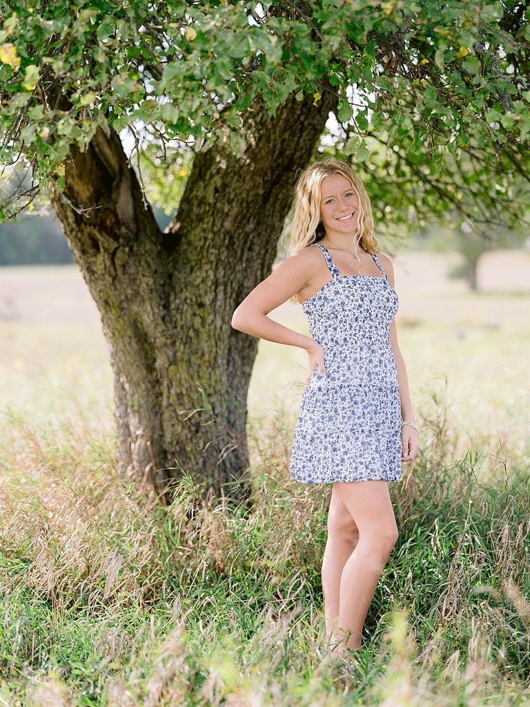 A high school senior poses for portraits in tall grass in Northern Michigan