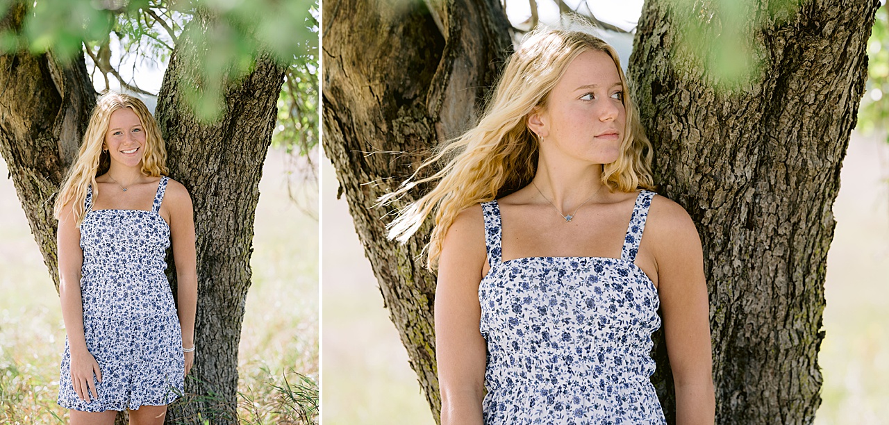 A high school senior stands next to a tree trunk in sunny Northern Michigan