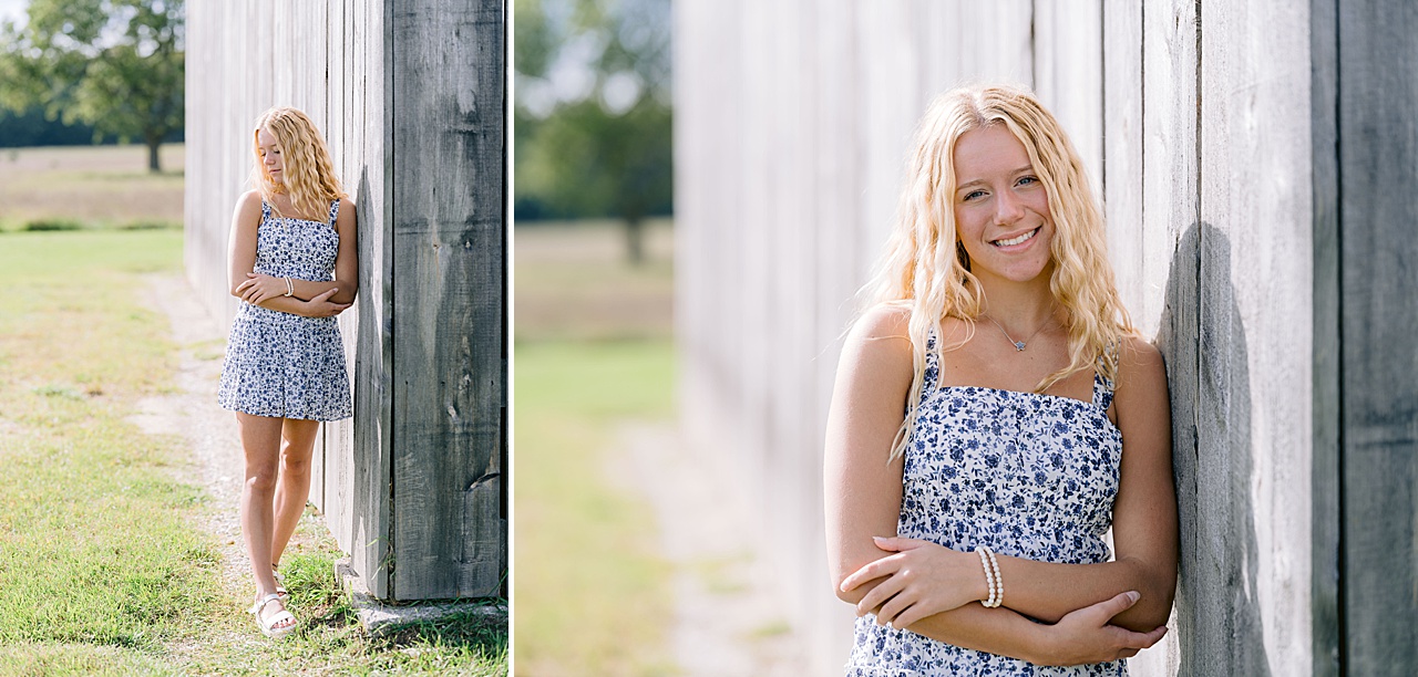 A high school senior poses next to a barn in the sun in Maple City, Michigan