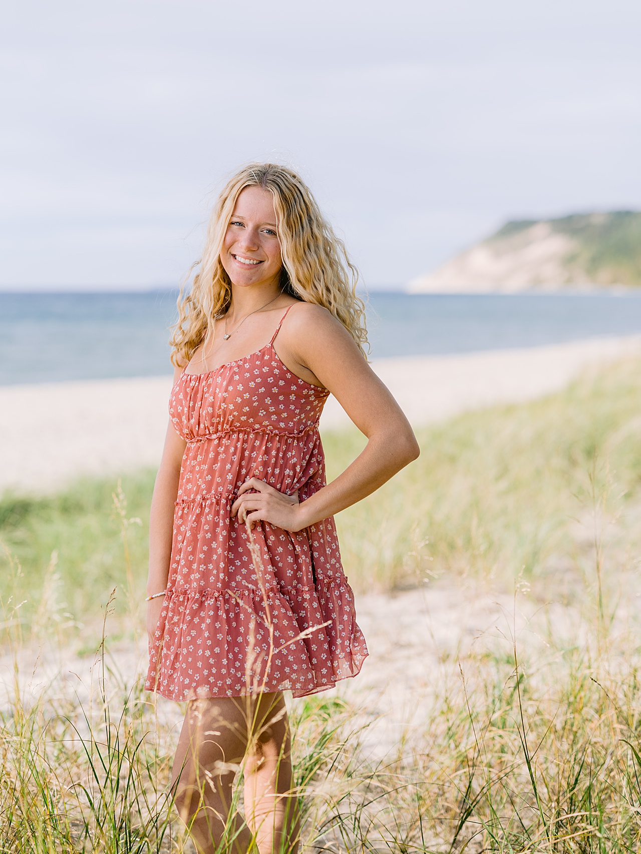A girl stands with hand on hip in Oneida, Michigan with dunes in the background