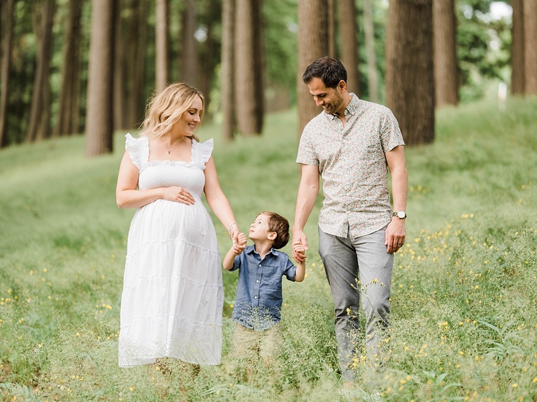 A mother and father look down at their son while walking through the woods in Northern Michigan