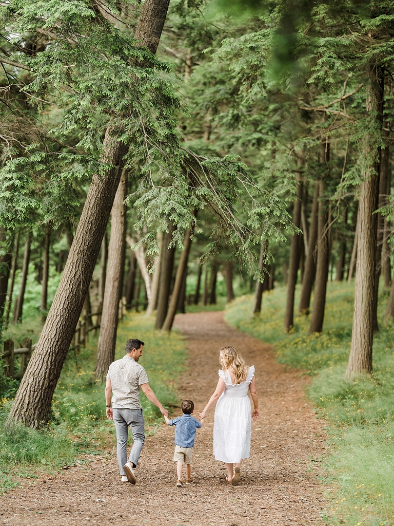 A man and woman walk down a wood chip path during Northern Michigan Maternity Family Portraits