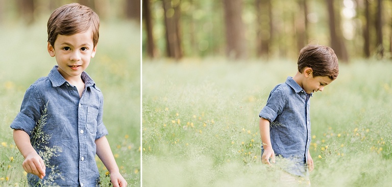 A little boy stands in a field of wild, yellow flowers and smiles with trees in the background