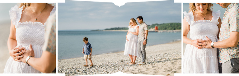 A man places his hand on his expectant wife's belly while their son plays on a rocky beach