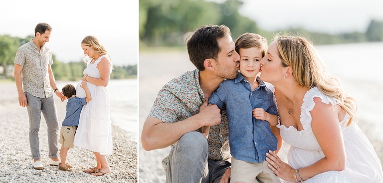 A young boy hugs his pregnant mother's belly while his father stands smiling on a sunny beach