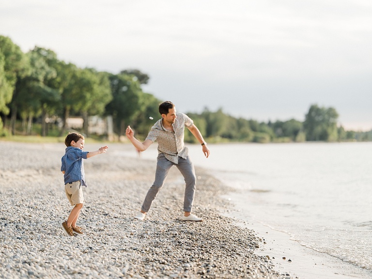 A man and a young boy throw rocks into Walloon Lake together on the beach
