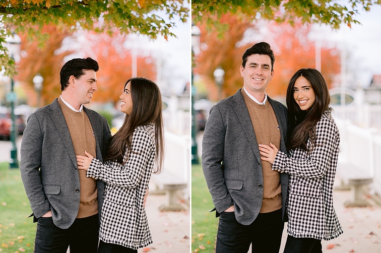 A couple pose for portraits under a tree in the fall in a Michigan park