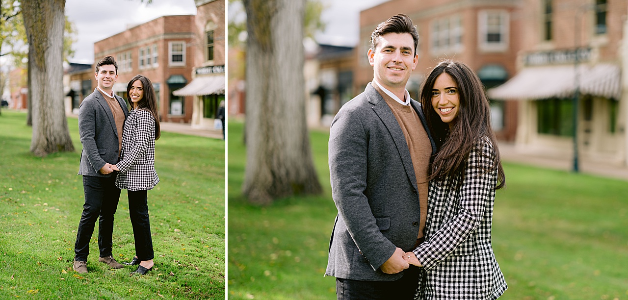 A couple poses for engagement portraits with brick buildings behind them