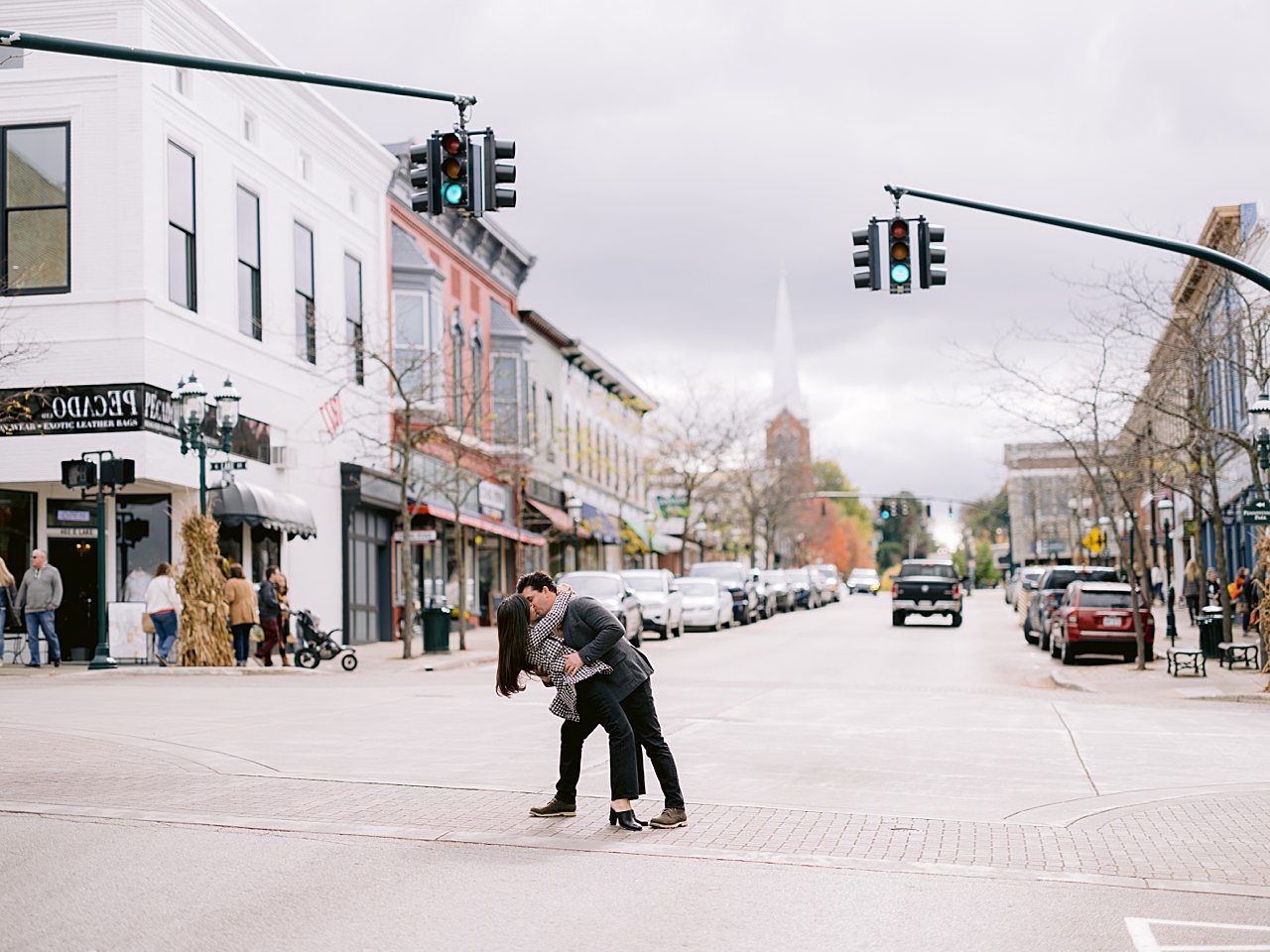 A couple share a kiss in a crosswalk under a green light in downtown Petoskey