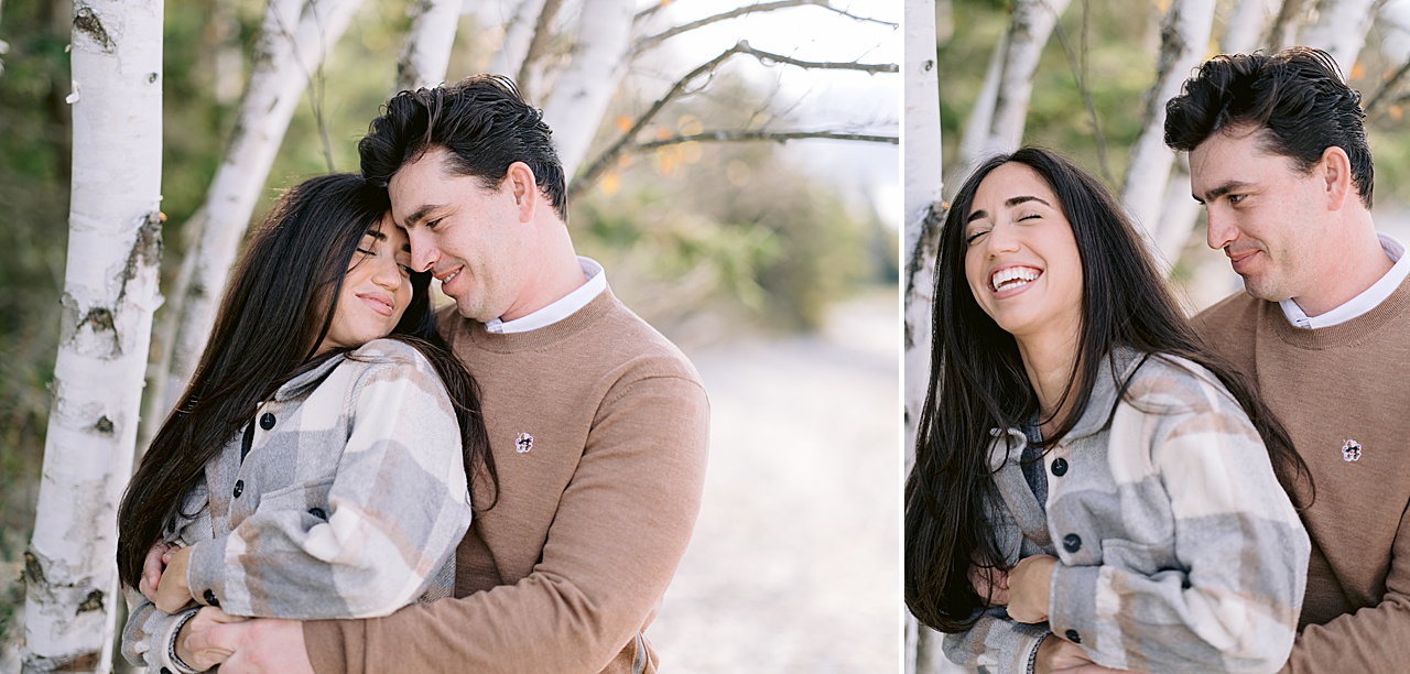 A woman wearing a flannel laughs with her fiancé near a white tree in Michigan