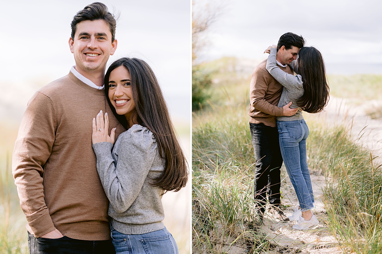 A couple lean into each other while standing in the sand and tall grass
