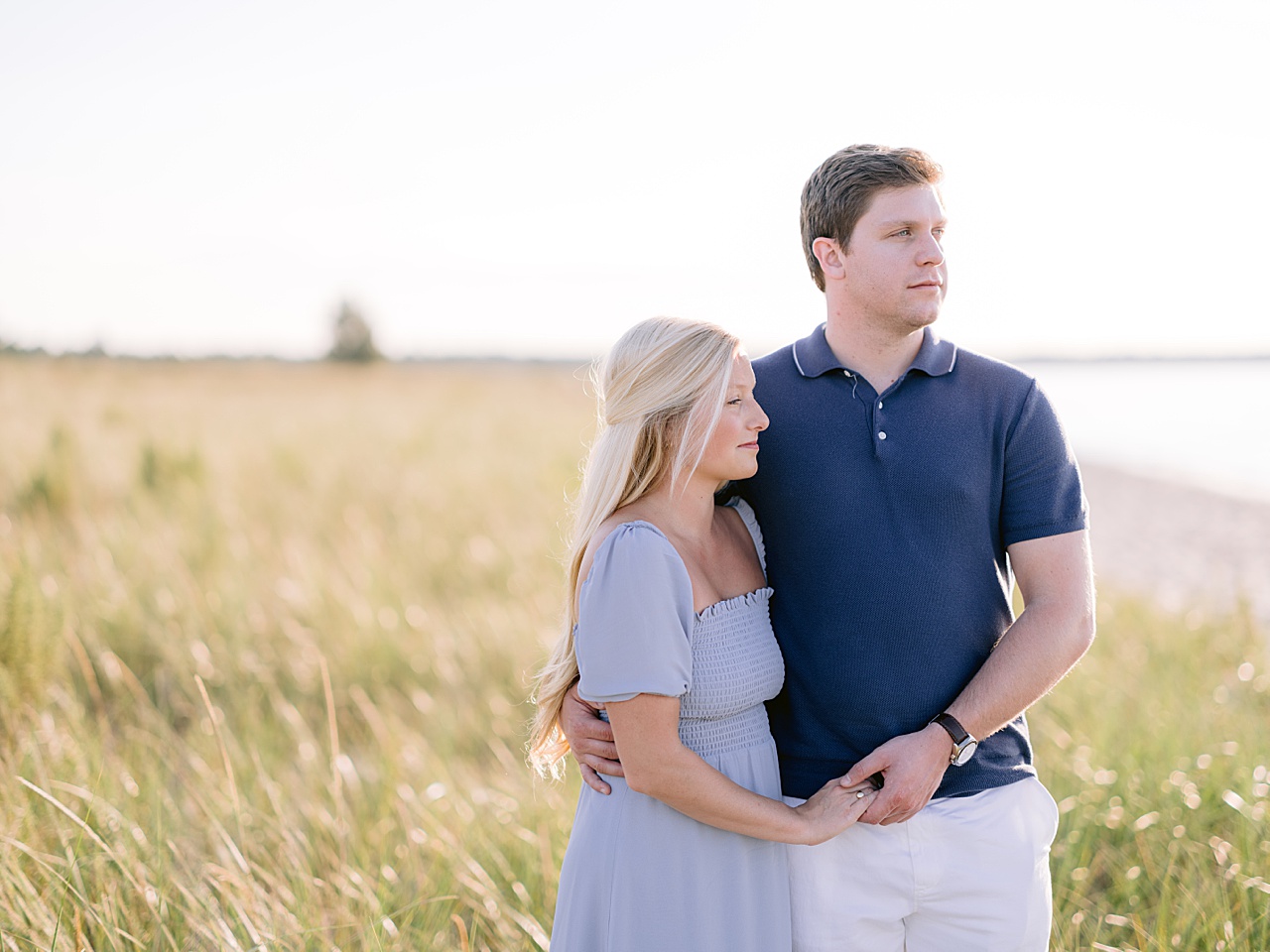 An engaged couple wearing outfits in tones of blue for their engagement session at a beach along the Sleeping Bear Dunes National Lakeshore
