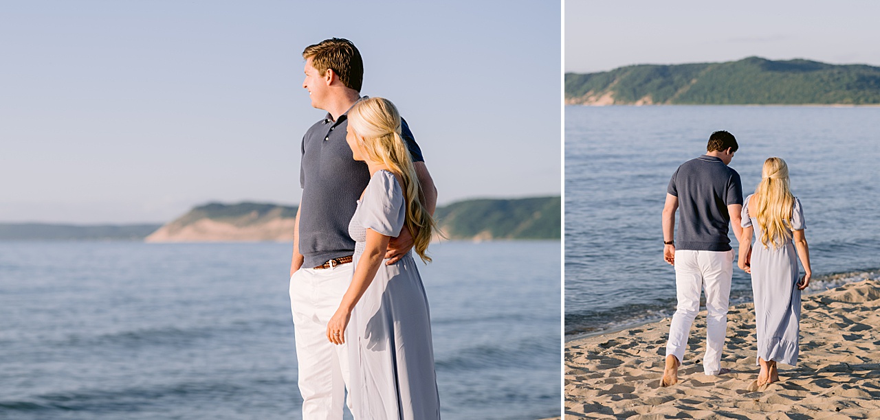 An engaged man and woman walking in the evening sunshine barefoot through the sandy beach with a lake and sand dunes in the background