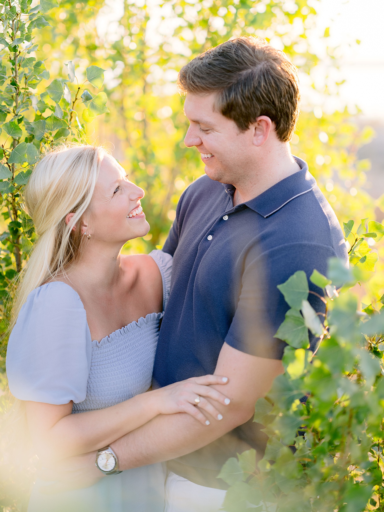 A happy engaged couple smiling at each other in a wooded area in Northern Michigan
