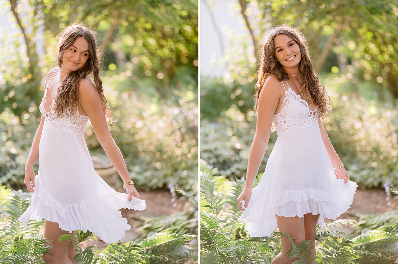 A young woman in a white dress spins in tall ferns for harbor springs senior portraits