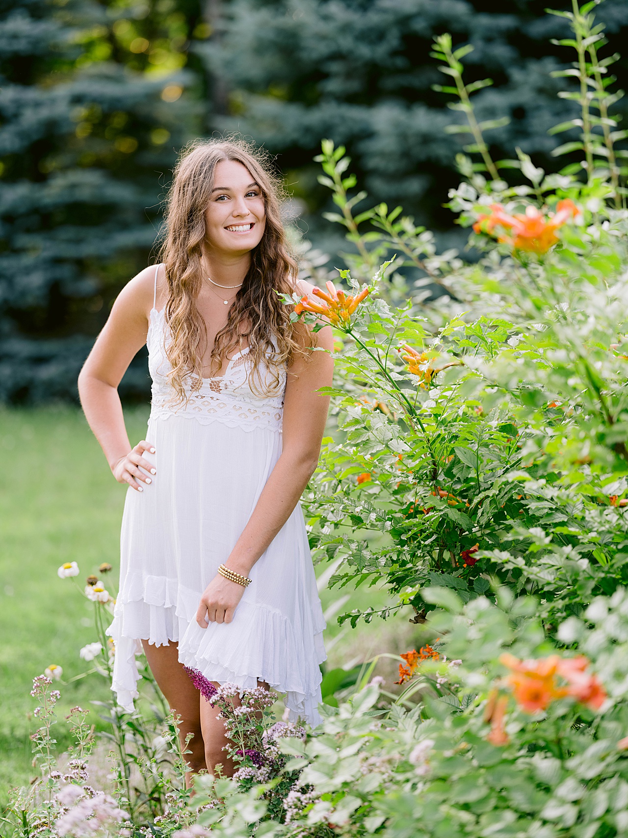 A young woman poses beside flowers for senior pictures in Northern Michigan