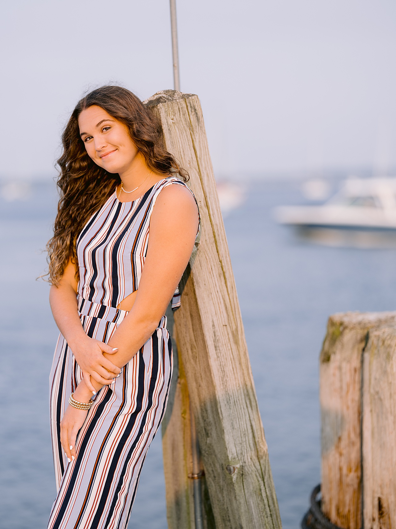 A northern Michigan senior poses in a striped jumpsuit for harbor springs senior portraits