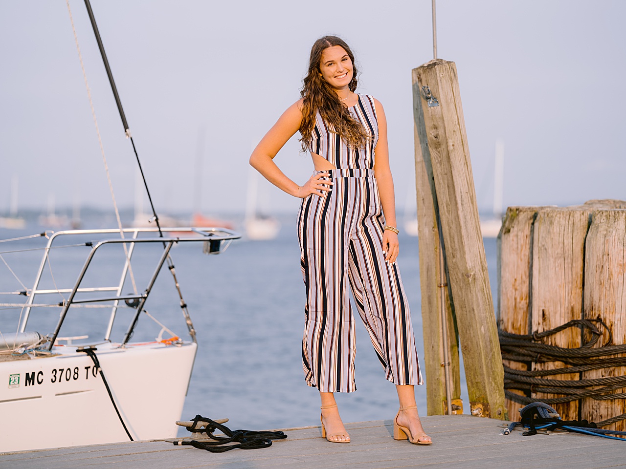 A high school senior stands with her hand on her hip beside a docked boat in michigan