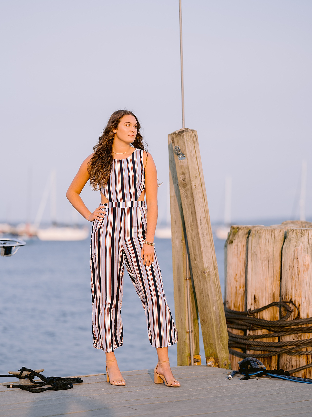 A high schooler with long brown hair looks into the distance while on a dock in Northern Michigan