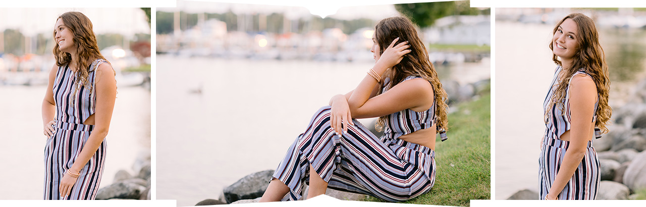 A girl with long brown hair in a striped jumper looks out at a lake for harbor springs senior portraits