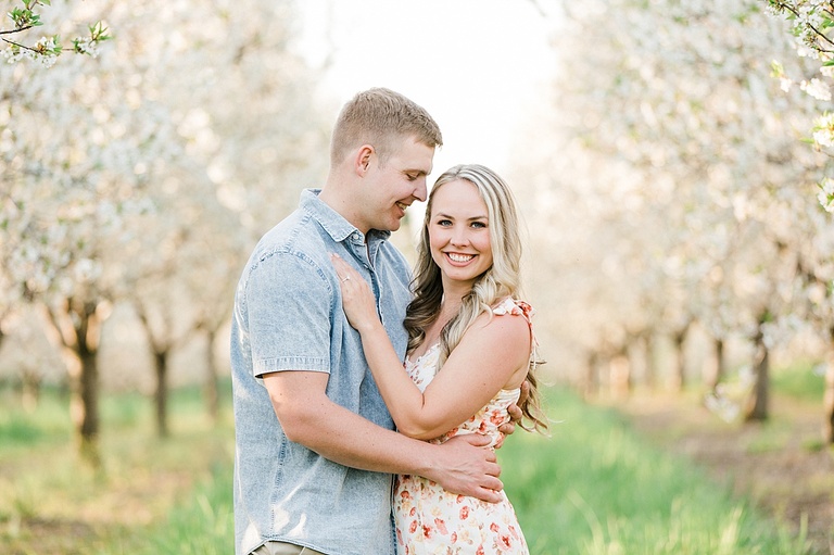 A man looks smiling at his fiancé while she looks into the camera and smiles