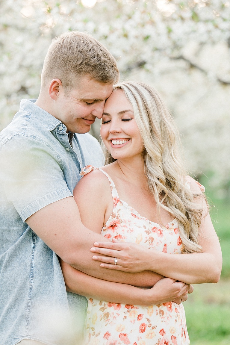 A man stands with his arms around a woman while they press their foreheads together