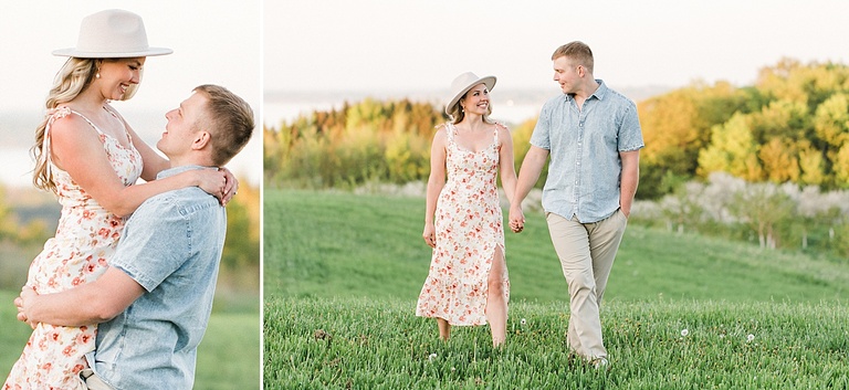 A man and woman walk through a lush, green field of grass while holding hands and smiling at each other