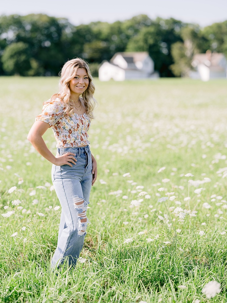 A girl stands in a field of white orlaya in the summer in Northern Michigan