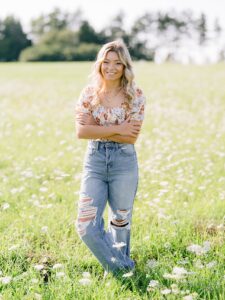 A high school girl poses for michigan countryside senior portraits in a field of orlaya