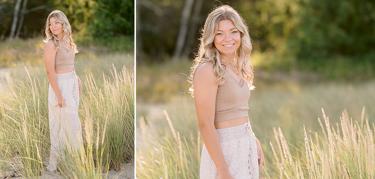 A high school girl poses in tall grass that is lit by golden sunshine in northern michigan