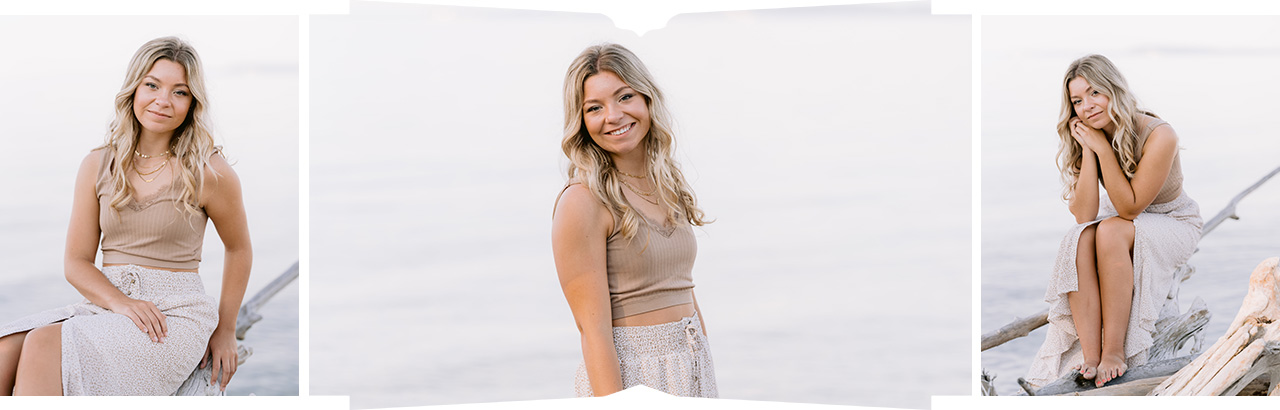 A girl sits on a piece of driftwood and poses for senior portraits