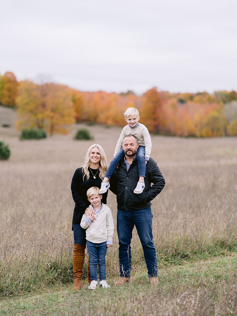 A family poses near a field on an overcast day for michigan fall family portraits