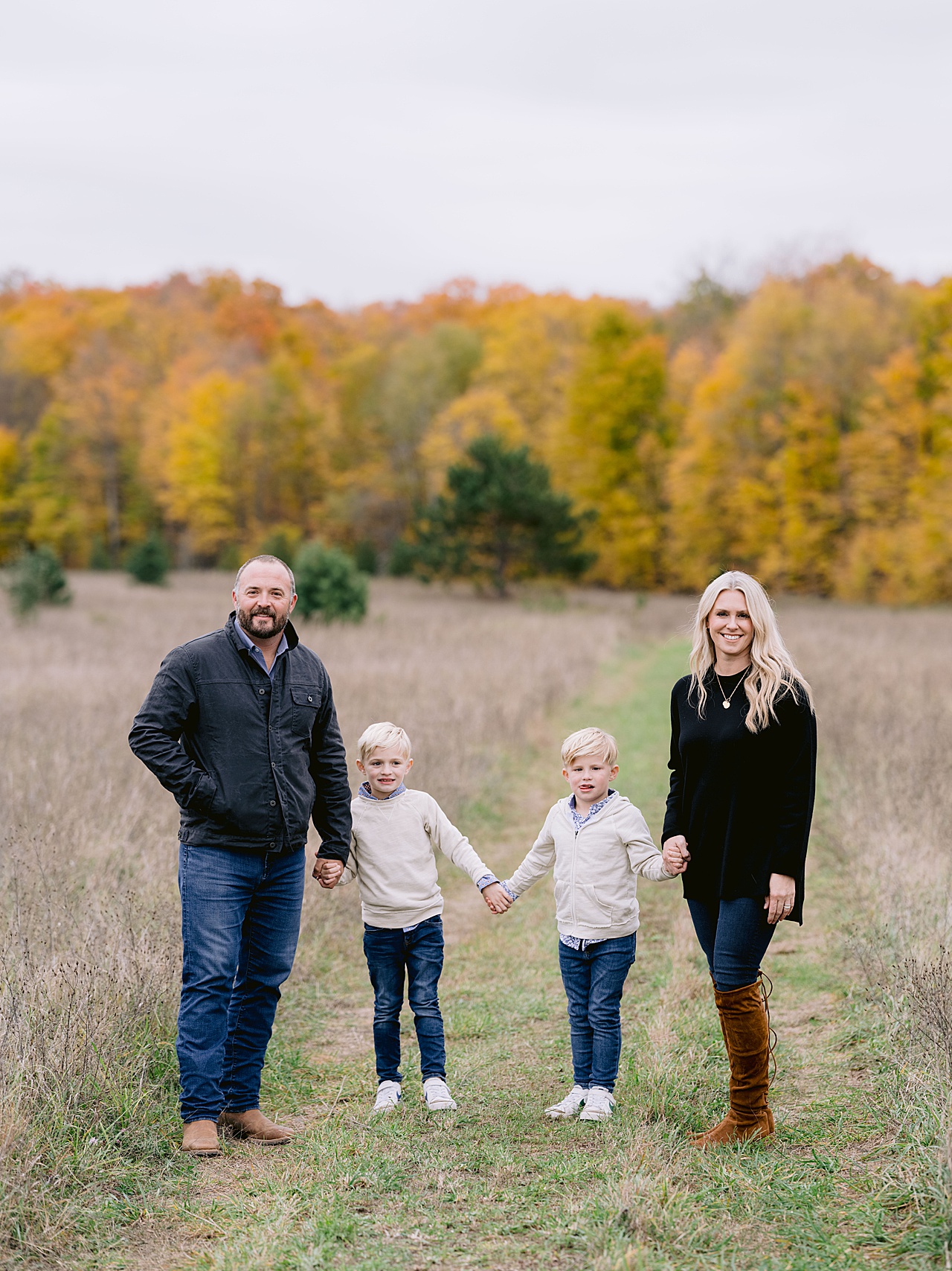 A mother and father hold hands with their two young sons for michigan fall family portraits