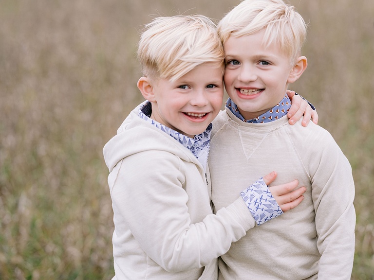 Two young boys stand with their arms around each other and pose for michigan fall family portraits