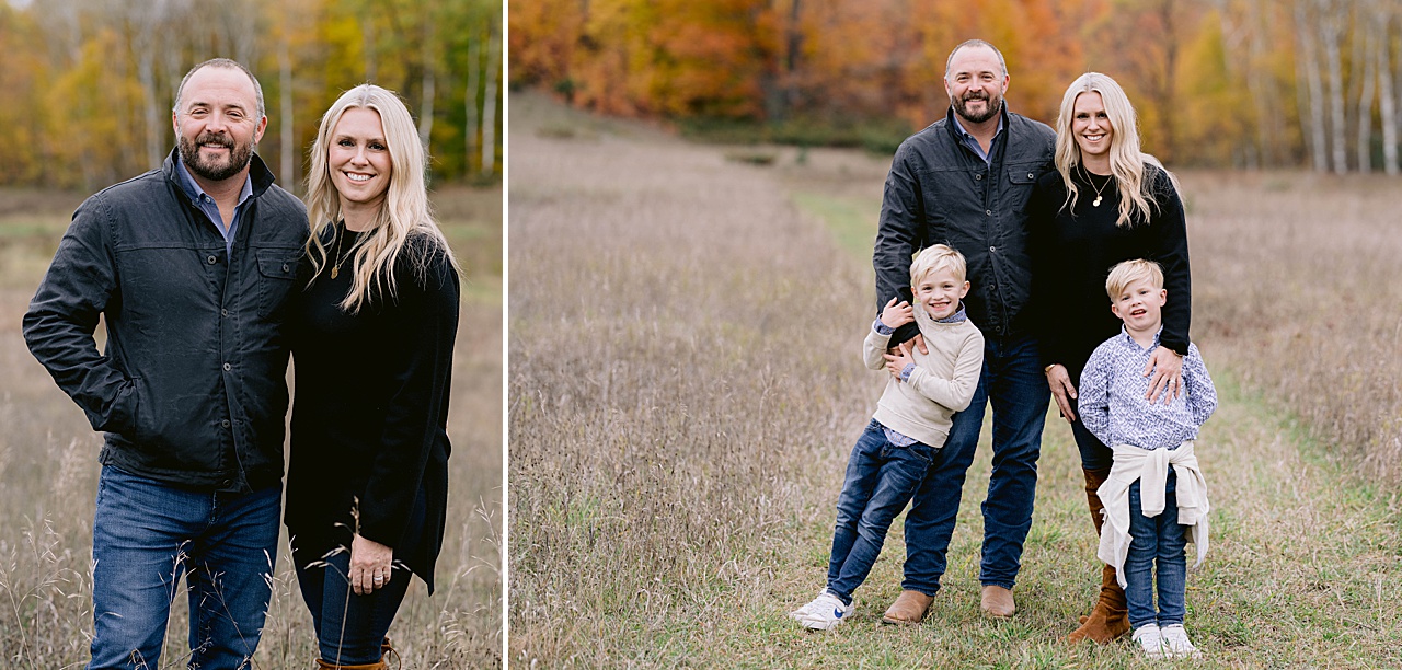 A family of four stands in a field in the fall in michigan with orange and yellow trees behind them