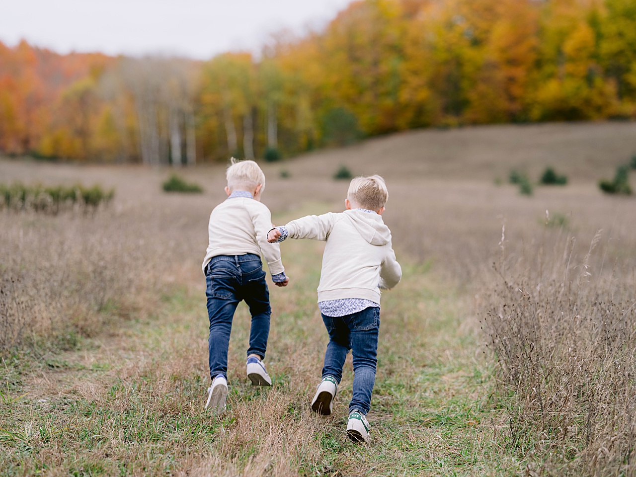 Two boys race each other up a path in the fall in Northern Michigan
